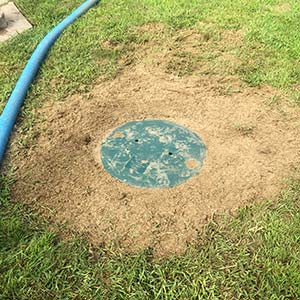 Septic tank cover exposed on the ground.